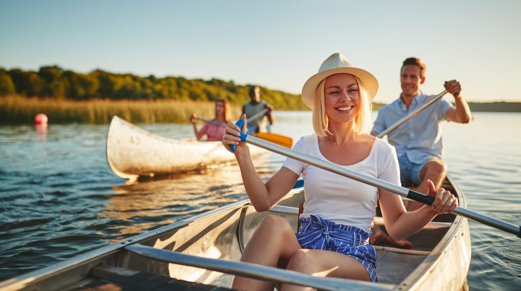 Lachende junge Frau fährt mit ihrem Partner im Kanu