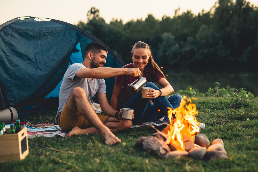 Junges glückliches Paar sitzt am romantischen Lagerfeuer